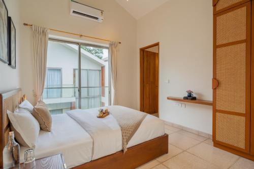 a bedroom with a bed and a large window at ELIVAAS 3 BHK with Pvt outdoor Pool - Mirai Gemini in Vagator