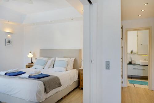 a white bedroom with a large bed and a bathroom at Blueros Luxury Villa in Megas Yialos-Nites