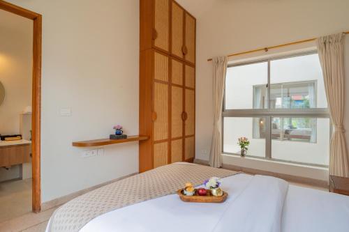 a bedroom with a bed with a bowl of fruit on it at ELIVAAS 3 BHK with Pvt outdoor Pool - Mirai Gemini in Vagator