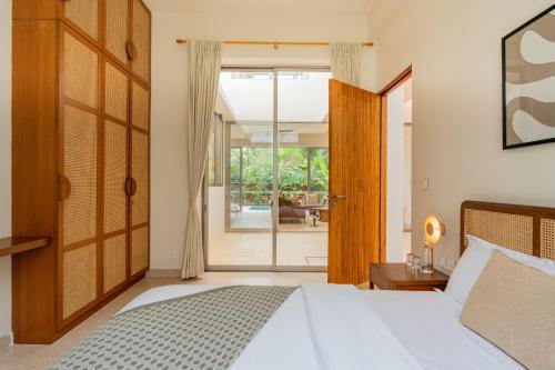 a bedroom with a bed and a sliding glass door at ELIVAAS 3 BHK with Pvt outdoor Pool - Mirai Gemini in Vagator
