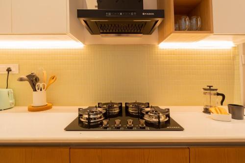 a stove top in a kitchen with yellow tiles at ELIVAAS 3 BHK with Pvt outdoor Pool - Mirai Gemini in Vagator