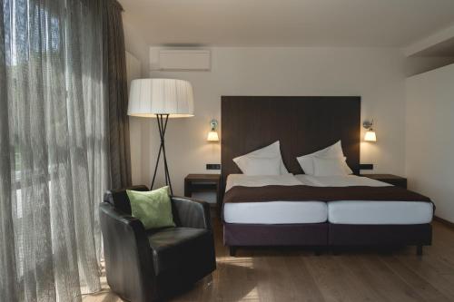 a hotel room with a bed and a chair at Golfhotel Gut Neuenhof in Fröndenberg