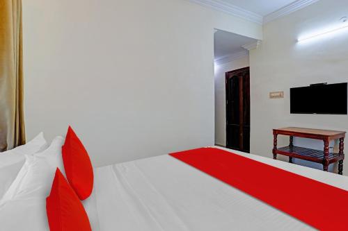 a bedroom with a bed with a red blanket and a table at Hotel O Le Fort in Trivandrum