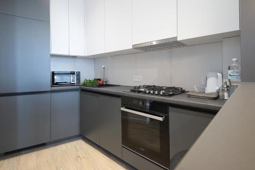 a kitchen with white cabinets and a stove top oven at FORUM apart in Lviv