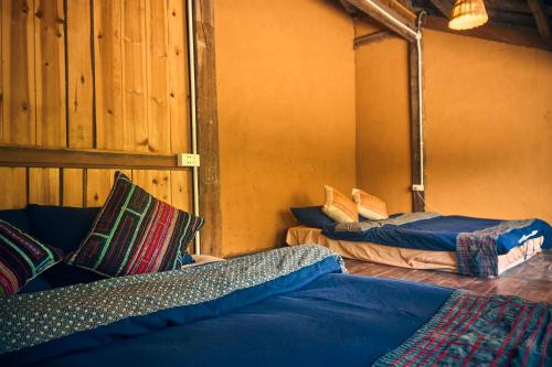 a room with two beds in a room with a wall at Sa Moc - La Maison House & Bungalow in Sa Pa