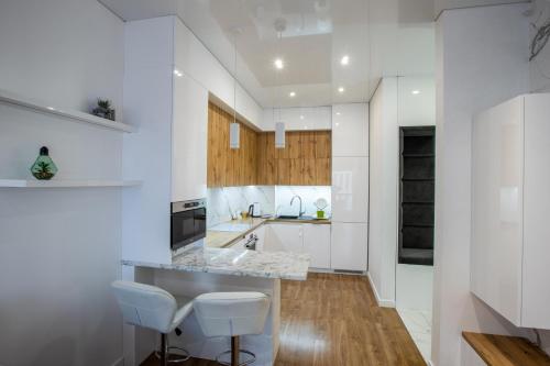 a kitchen with white cabinets and white stools at FORUM apart in Lviv