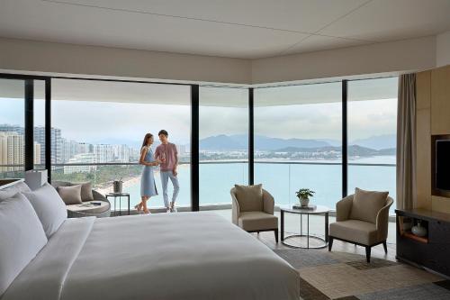a couple standing in a hotel room with a large bed at The Shanhaitian Resort Sanya, Autograph Collection in Sanya