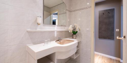 a white bathroom with a sink and a mirror at PLAZA INN Rieker Stuttgart Hauptbahnhof in Stuttgart