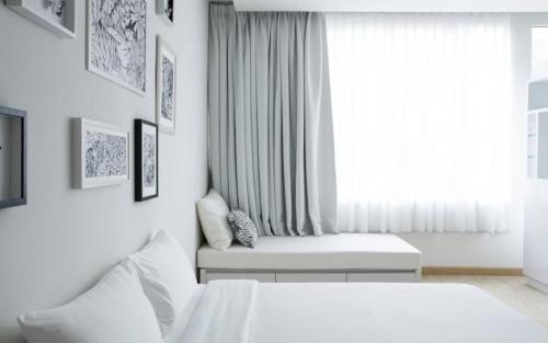 a white bedroom with two beds and a window at Beat Hotel Bangkok in Bangkok