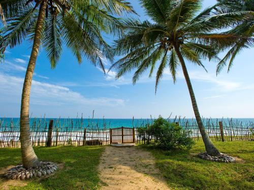 two palm trees and a gate at the beach at Villa Ocean's Edge in Ranna