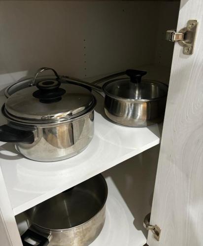 three pots and pans on a shelf in a kitchen at Stylish and Cozy Guest Suite in Calgary