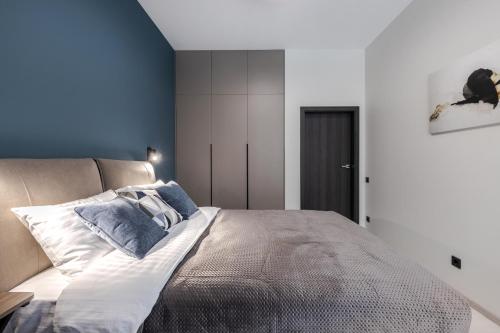 a bedroom with a large bed with blue walls at FORUM apart in Lviv