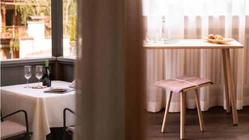 a table with a chair and a table with wine glasses at Flora Hotel & Suites in Merano