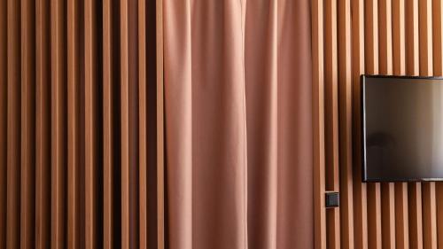 a television hanging on a wall next to a curtain at Flora Hotel & Suites in Merano