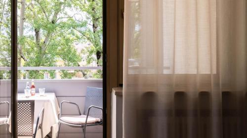 a table and chair in a room with a window at Flora Hotel & Suites in Merano