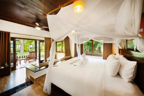 une chambre avec un lit blanc à baldaquin dans l'établissement Diamond Bay Resort & Spa, à Nha Trang