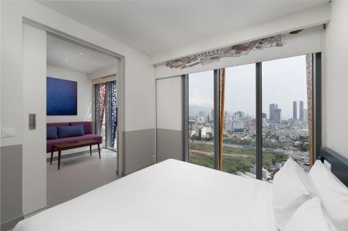 a bedroom with a view of a city at Wink Hotel Can Tho Ninh Kieu Wharf - 24hrs Stay & Rooftop Pool Bar in Can Tho