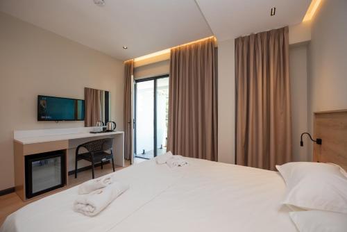 a hotel room with a bed and a desk and a television at Calma Boutique Hotel in Vlorë
