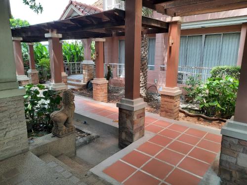 eine Veranda mit einer Steinstatue unter einer Pergola in der Unterkunft Bangkok Resort and Spa in Ban O Pao