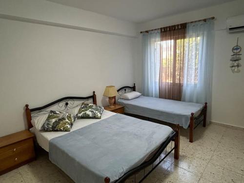 a bedroom with two beds and a window at Seaview apartment with garden & pool in Paphos City