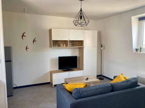 a living room with a blue couch and a tv at L'écrin du général in Armentières