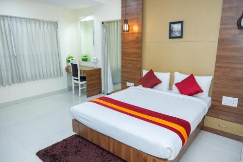 1 dormitorio con cama con almohadas rojas y escritorio en Ishwerya Suites, en Bangalore