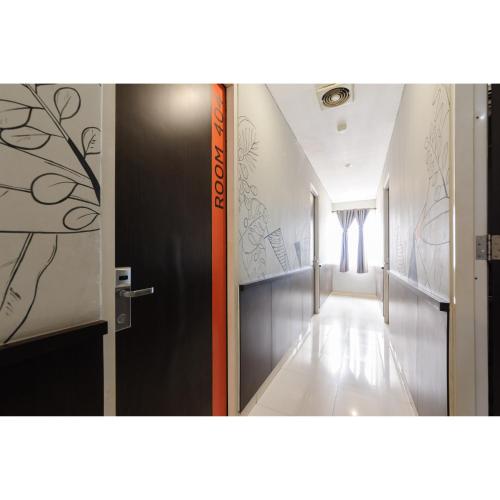 a corridor with a door and a hallway with paintings on the walls at RedDoorz Plus near Grand Indonesia Jakarta in Jakarta