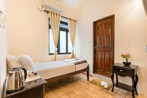 a small bedroom with a bed and a window at The Tamarind Hotel - A Boutique Heritage Stay, Anjuna - Goa in Anjuna