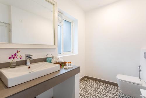 a white bathroom with a sink and a mirror at The Tamarind Hotel - A Boutique Heritage Stay, Anjuna - Goa in Anjuna