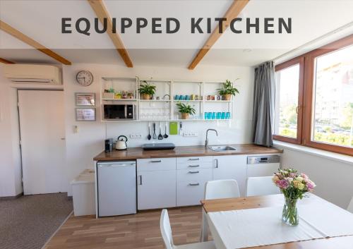 a kitchen with white cabinets and a table at VOUSATÁ DÁMA - PS3 - Parking free in Prague