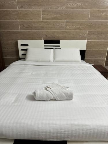 a white bed with a pair of shoes on it at The Elite Inn in Mahabalipuram