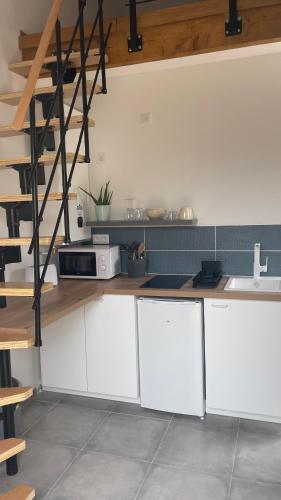 une cuisine avec des placards blancs et un escalier dans l'établissement Studio calme avec jardin et parking privé, à La Ciotat