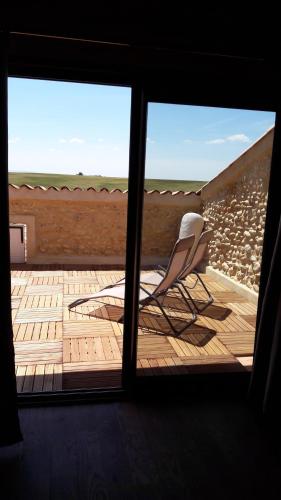 une chaise assise sur une terrasse en bois regardant par une fenêtre dans l'établissement chambre à la campagne au milieu des lavandes, à Valensole