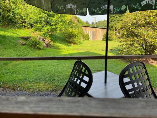 two chairs sitting on a porch under an umbrella at Auberge Restaurant La Roseraie in Grandrupt