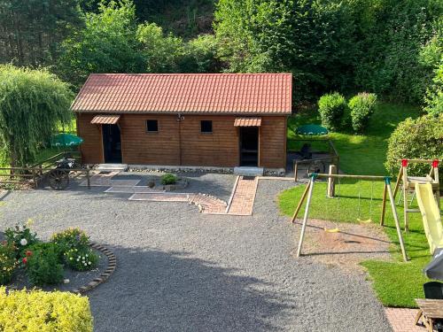 a small wooden building with a playground in a yard at Auberge Restaurant La Roseraie in Grandrupt
