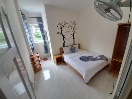 a bedroom with a bed with a tree on the wall at MrLee Dalat House in Da Lat
