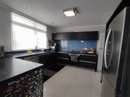 a kitchen with black cabinets and a stainless steel refrigerator at Home with sea views in New Plymouth