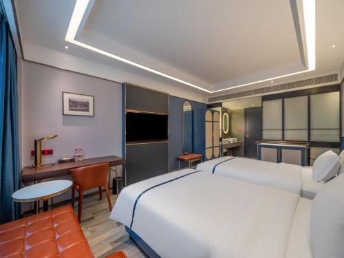 a bedroom with a large white bed and a desk at 西安钟楼枫渡酒店永兴坊地铁站店 in Xi'an