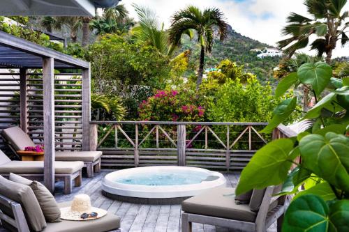 a hot tub on a patio with chairs and trees at Hotel Manapany in Gustavia