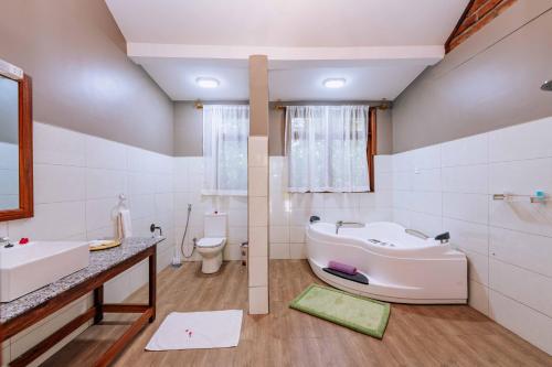 a bathroom with a tub and a sink and a toilet at Under The Shade Safari Lodge in Arusha