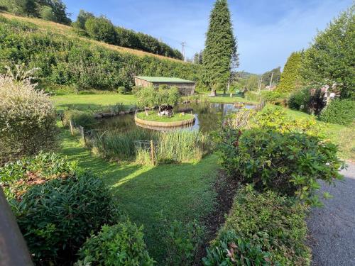 a garden with a pond in the middle at Auberge Restaurant La Roseraie in Grandrupt