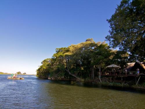 a boat on a river next to a restaurant at Ndhovu Safari Lodge in Mahango