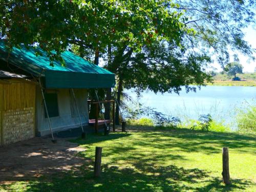a house with a green roof next to a lake at Ndhovu Safari Lodge in Mahango