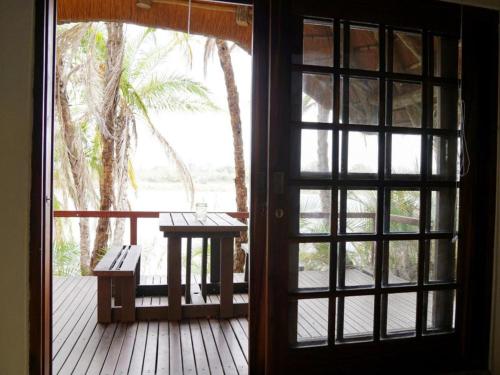 an open door to a porch with a table and a bench at Ndhovu Safari Lodge in Mahango