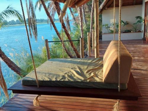a bed swing on a porch with a view of the water at Ndhovu Safari Lodge in Mahango