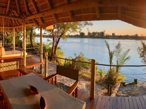a view of a river from a resort with a table and chairs at Ndhovu Safari Lodge in Mahango