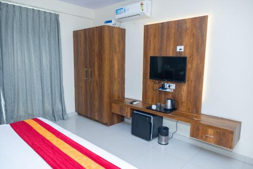 a bedroom with a bed and a tv and wooden cabinets at Ishwerya Suites in Bengaluru