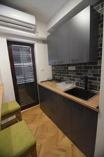a kitchen with black cabinets and a sink at Station 44 Apartments in Bitola