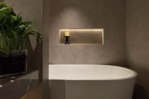 a bathroom with a bath tub with a candle on the wall at Phoenix Hall House Hotel in Fenghuang