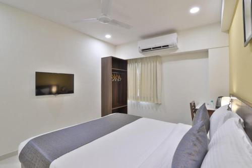 a bedroom with a white bed and a tv at Leo Hotel in Ahmedabad